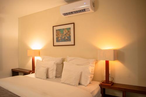 a bedroom with a bed with pillows and two lamps at Pousada da Cyssa in Búzios