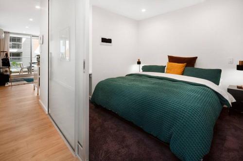 sypialnia z łóżkiem z zielonymi i pomarańczowymi poduszkami w obiekcie Morphett City Chic 1 bdrm Kitchen Wifi Pool w mieście Adelaide
