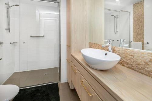 a bathroom with a white sink and a shower at Morphett City Chic 1 bdrm Kitchen Wifi Pool in Adelaide