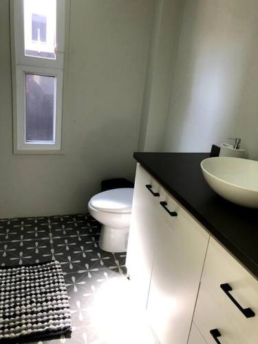 a bathroom with a white toilet and a sink at Moderna casa nueva en hermosa y soleada parcela in La Serena