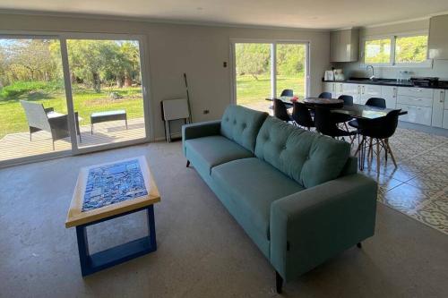 a living room with a green couch and a table at Moderna casa nueva en hermosa y soleada parcela in La Serena