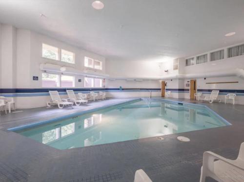 a large swimming pool with chairs in a building at Sunday River Ski In Ski Out Mountain View Condo with Hot Tub Pool and Sauna! in Newry