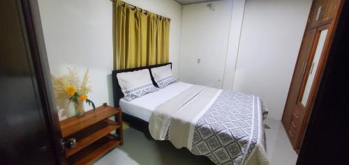 a bedroom with a bed and a yellow curtain at Departamentos extension Casa Paraíso in Manta