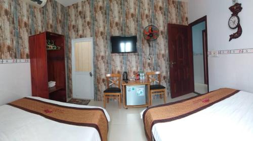 a bedroom with two beds and a tv on a wall at Ngan Giang Guesthouse in Phú Quốc