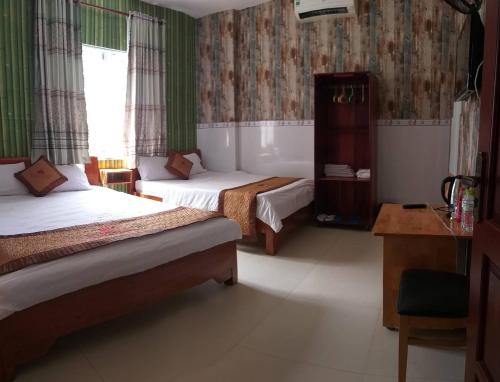 a hotel room with two beds and a table and a desk at Ngan Giang Guesthouse in Phu Quoc