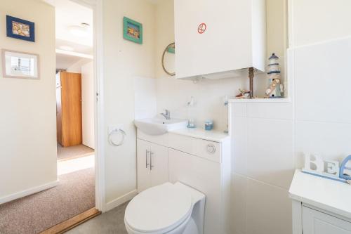 a white bathroom with a toilet and a sink at 18 Undercliffe in Felixstowe