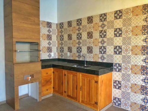 a kitchen with a sink and a tiled wall at Vila Verde Chalés-Serro in Sêrro