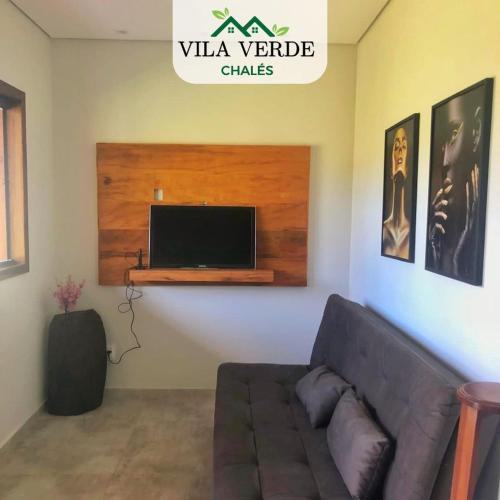 a living room with a couch and a flat screen tv at Vila Verde Chalés-Serro in Sêrro