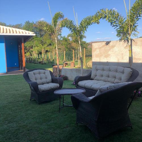two chairs and a couch and a table in the grass at Vila Verde Chalés-Serro in Sêrro