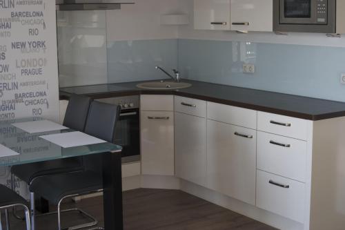 uma cozinha com armários brancos, um lavatório e uma mesa em Hommage Appartements em Waren
