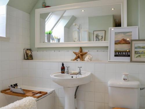 a bathroom with a sink and a toilet and a mirror at 1 The Courtyard in Kinneff