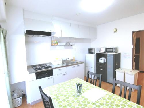 a kitchen with a table and chairs and a kitchen with white cabinets at Simple Stay Beppu in Beppu