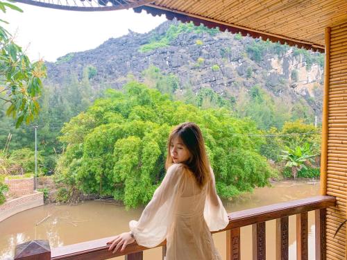a young girl standing on a balcony looking out at a river at Trang An Resort in Ninh Binh