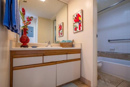 a bathroom with a sink and a toilet and a vase with flowers at Sealodge E7 in Princeville