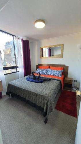 una camera da letto con un letto con cuscini arancioni e blu di Cómodo departamento en bellas artes con vista privilegiada a Santiago