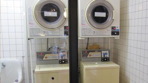 baño con 2 lavadoras y lavamanos en Kyukamura Nyuto-Onsenkyo, en Senboku