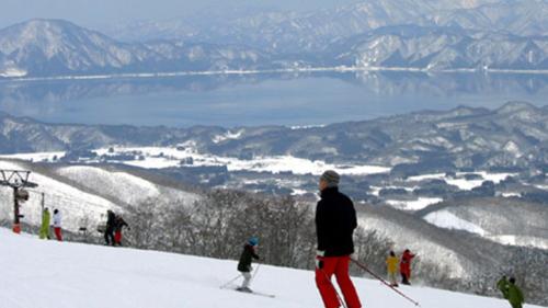 a group of people skiing down a snow covered slope at Kyukamura Nyuto-Onsenkyo in Senboku