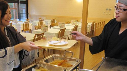 two women eating food on a table in a restaurant at Kyukamura Nyuto-Onsenkyo in Senboku