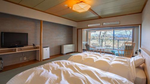 a bedroom with a bed and a flat screen tv at Kyukamura Kesennuma-Ohshima in Kesennuma