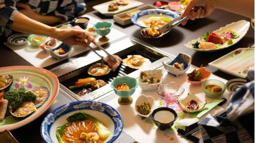 a table filled with plates and bowls of food at Kyukamura Kesennuma-Ohshima in Kesennuma