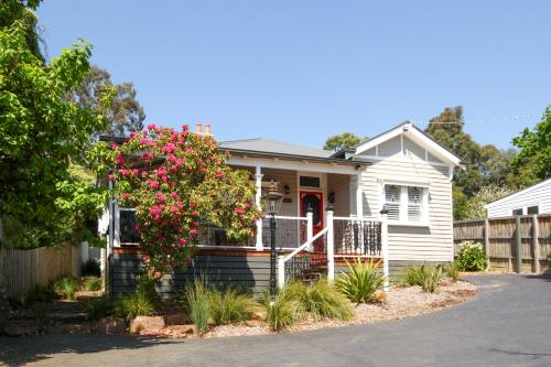 a white house with a flowering bush in front of it at Vintage Charm On St Leonards in Healesville