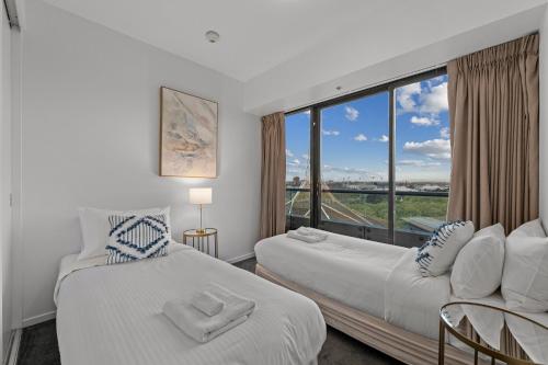 - 2 lits dans une chambre avec une grande fenêtre dans l'établissement Exclusive Stays - Gallery Tower, à Melbourne