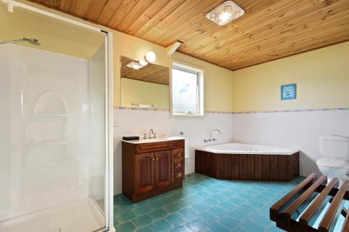 a bathroom with a tub and a sink and a shower at Clovelly Cottage in Metung