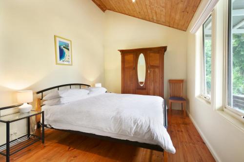 a bedroom with a white bed and a window at Clovelly Cottage in Metung