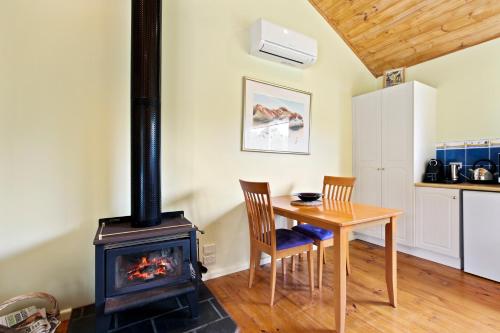 a room with a wood stove and a table and chairs at Clovelly Cottage - Cosy Metung Escape in Metung