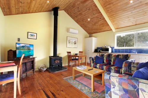 a living room with a couch and a wood stove at Clovelly Cottage - Cosy Metung Escape in Metung
