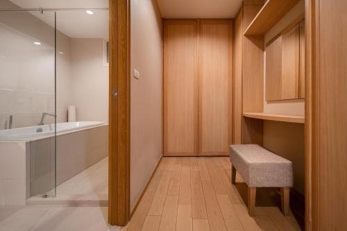 a bathroom with a shower and a bath tub and a stool at North Park Serviced Apartment Bangkok in Bangkok