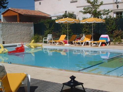 une piscine avec chaises et parasols dans l'établissement Gîte familial avec piscine chauffée, jardin privé et équipements bébé en pleine propriété viticole. - FR-1-653-18, à Saint-Cybardeaux