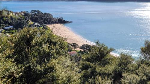 a view of a beach with trees and water at Margaritaville Hahei in Hahei