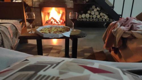 a table with a pizza and two glasses of wine at Chácara Engenho in Itamonte