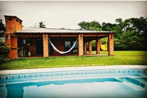 uma casa de tijolos com uma piscina em frente em Luz de Luna Ubicación privilegiada frente a laguna y piscina em San Cosme
