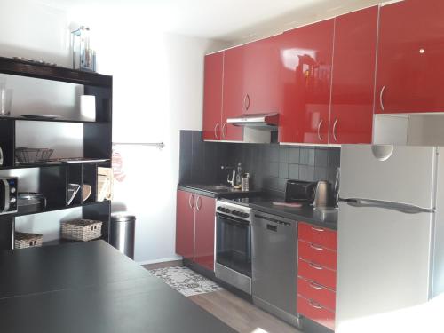 une cuisine avec des armoires rouges et un comptoir noir dans l'établissement Très beau T3 au pied des pistes pour 6/7 personnes à Villard-de-Lans - FR-1-689-48, à Villard-de-Lans
