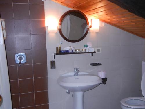 bagno con lavandino, specchio e servizi igienici di Mansarda 2 del Capitel a Commezzadura
