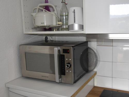 un micro-ondes posé sur une étagère dans une cuisine dans l'établissement Charmant 2P au Pied des Pistes avec Parking - 6 Personnes - FR-1-689-67, à Villard-de-Lans