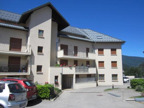 un grand bâtiment avec des voitures garées dans un parking dans l'établissement Studio spacieux 32m², 4 pers., centre de Villard-de-Lans, terrasse, parking, proche commodités - FR-1-689-96, à Villard-de-Lans