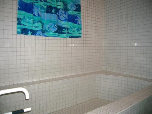 a white tiled bathroom with a tub with a painting at Appartement Villard-de-Lans, 2 pièces, 4 personnes - FR-1-689-94 in Villard-de-Lans