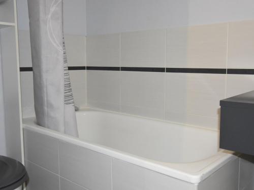 a white bath tub with a shower curtain in a bathroom at Studio Villard-de-Lans, 1 pièce, 4 personnes - FR-1-689-76 in Villard-de-Lans