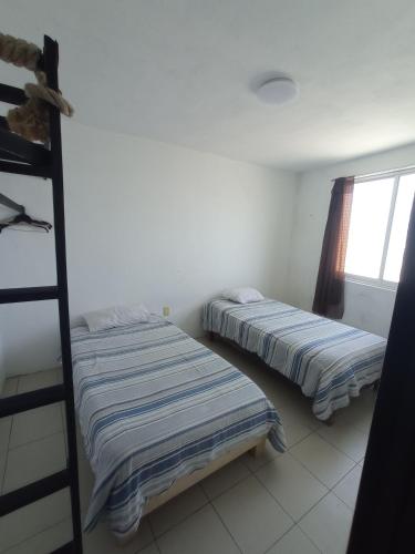 two beds in a room with a window at Hotelito Ejido in Sanctórum