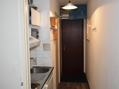 une petite cuisine avec un évier et une porte noire. dans l'établissement Studio Pied des Pistes à Villard-de-Lans - Côte 2000, 4 Pers. avec Ascenseur et Equipements Complets - FR-1-689-92, à Villard-de-Lans
