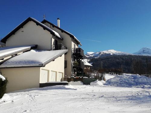 une maison couverte de neige avec des montagnes en arrière-plan dans l'établissement Studio double cabine 36m² au calme, jardinet et parking, à 10 min à pied du village - 4 pers. - FR-1-689-93, à Villard-de-Lans