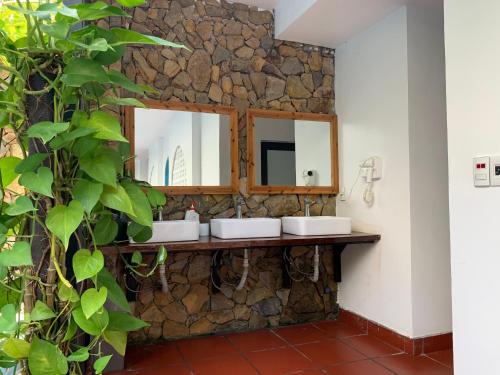 a stone bathroom with two sinks and a mirror at SECRET GARDEN Hostel - WANDERNEST Cat Ba in Cat Ba
