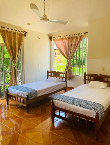 two beds sitting in a room with windows at Casa Karma in Puerto Escondido