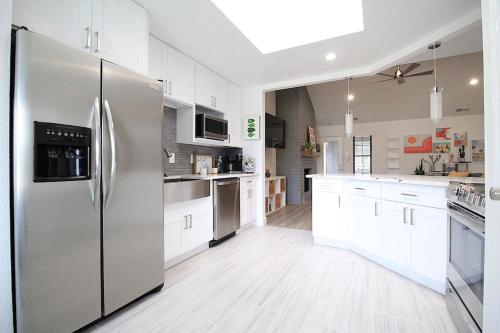 a kitchen with a stainless steel refrigerator and white cabinets at The Sleepy Fox in Plano