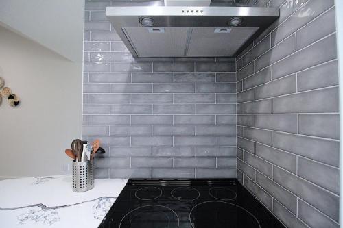 a kitchen with a tile wall with a stove at The Sleepy Fox in Plano