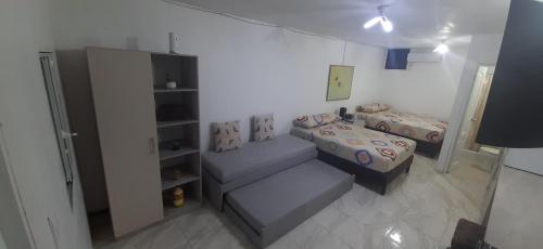 Habitación pequeña con 2 camas y sofá en Perla's Suites, en Guayaquil