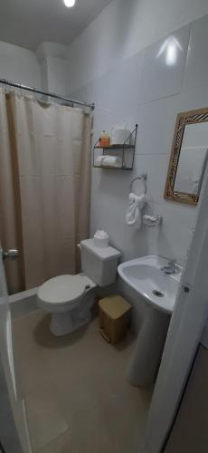 a bathroom with a toilet and a sink and a shower at Perla's Suites in Guayaquil